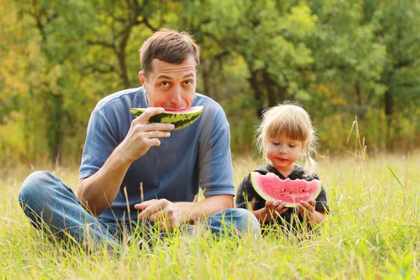 Bella bambina con suo padre mangia anguria in natura — Foto Stock