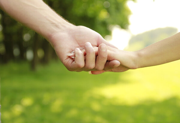 two hands of a loving couple on nature