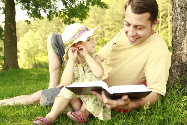 Padre joven con su pequeña hija lee la Biblia — Foto de Stock