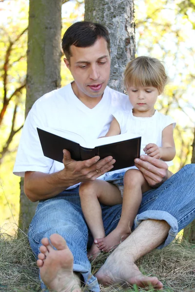 Young father with his little daughter reads the Bible — Stock Photo, Image