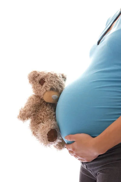 Una mujer embarazada con un oso de peluche sobre un fondo blanco — Foto de Stock