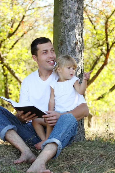 Padre joven con su pequeña hija lee la Biblia —  Fotos de Stock