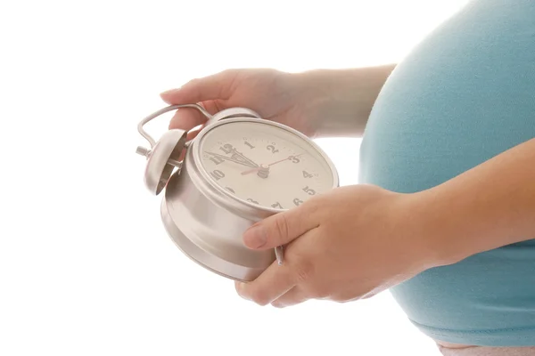 Een zwangere vrouw met een klok op een witte achtergrond — Stockfoto