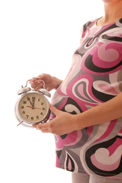 De zwangere vrouw op een witte achtergrond met een klok — Stockfoto