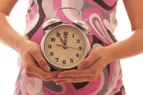 La mujer embarazada sobre un fondo blanco con un reloj — Foto de Stock