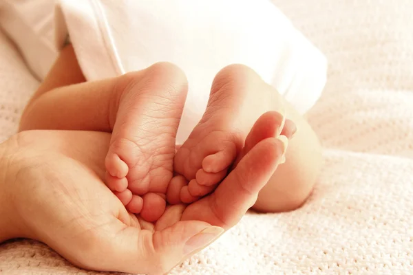 Mom holds the legs of newborn — Stock Photo, Image