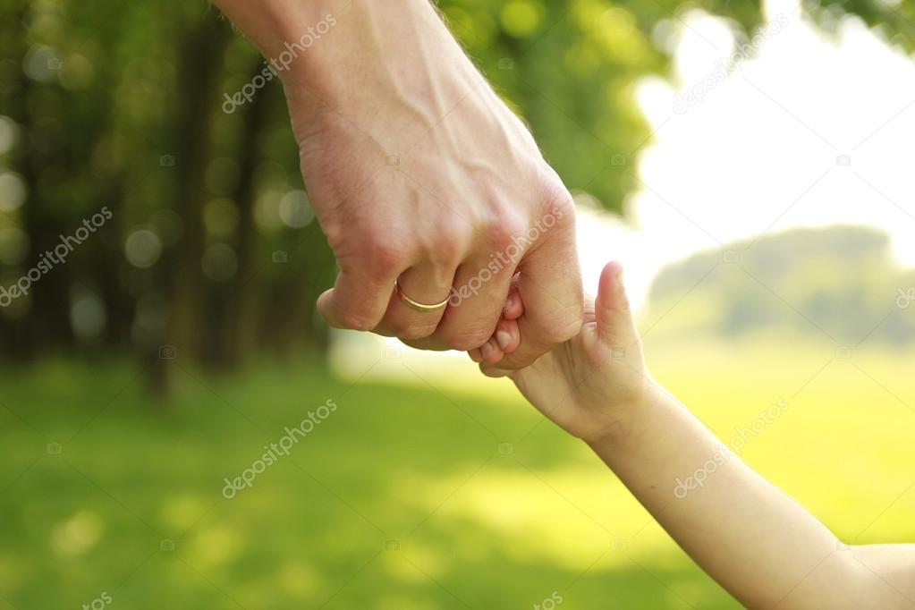 Parent holds the hand of a child