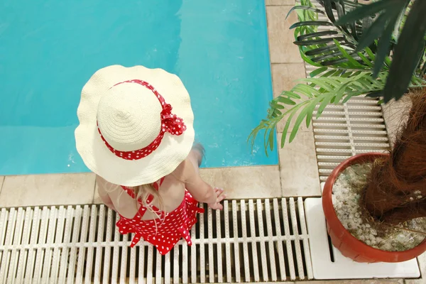 Little girl in a hat floating in the pool — Stock Photo, Image
