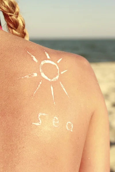 Of sun cream on the female back on the beach — Stock Photo, Image