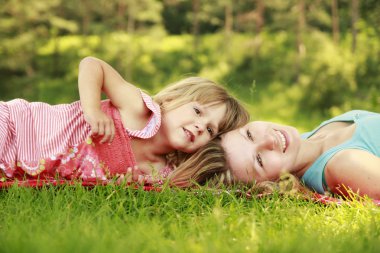 Anne ve küçük kızı çimenlerin üzerinde oynama