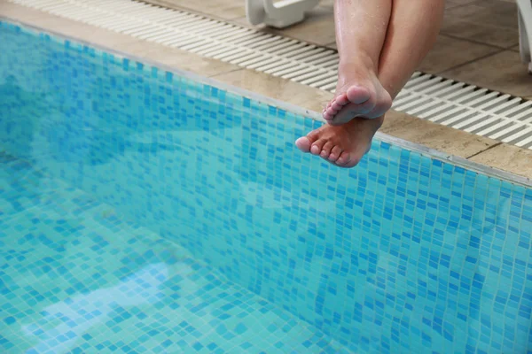 Piernas femeninas en la piscina de agua — Foto de Stock