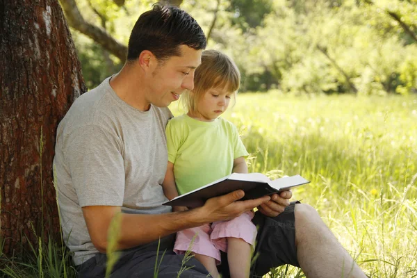 Jonge vader met zijn dochtertje leest de Bijbel — Stockfoto