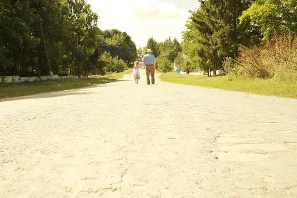 Dziadek z wnuczka spacerem wzdłuż drogi — Zdjęcie stockowe