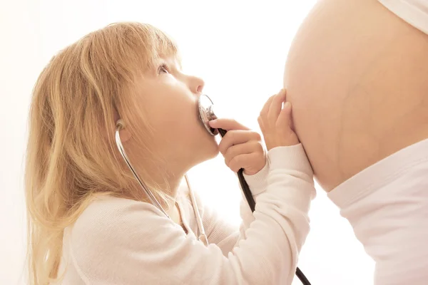 Těhotná žena s dítětem na bílém pozadí s statoscope — Stock fotografie