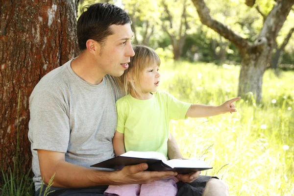 Νεαρό πατέρα με την κόρη του λίγο διαβάζει την Αγία Γραφή — Φωτογραφία Αρχείου