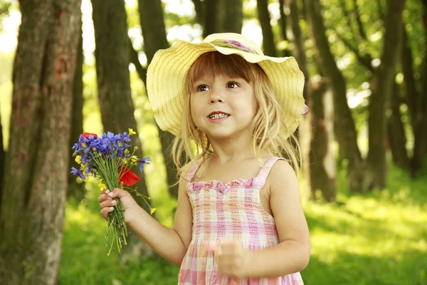 Όμορφο κοριτσάκι στη φύση με ένα μπουκέτο λουλούδια — Φωτογραφία Αρχείου
