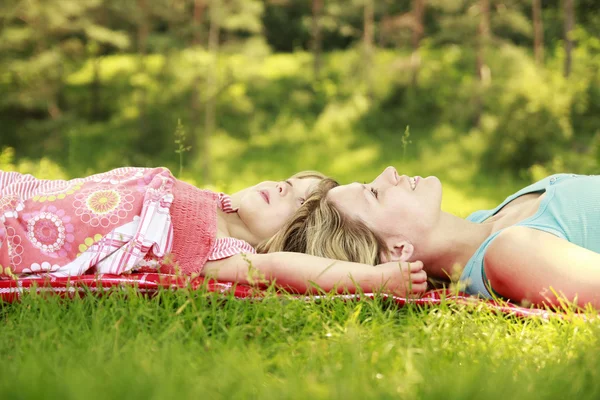 Mama en haar dochtertje liggen op het gras — Stockfoto