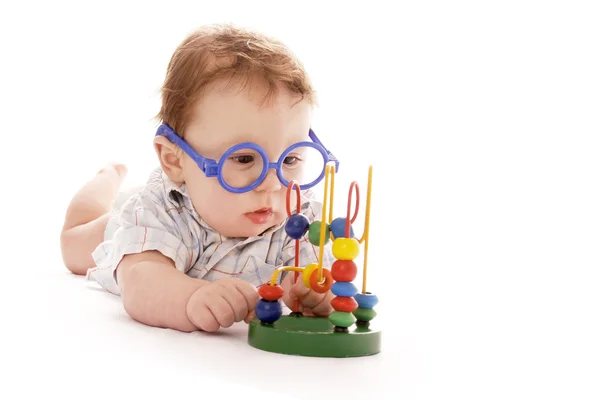 Infant baby on a white background in glasses with a toy — Stock Photo, Image