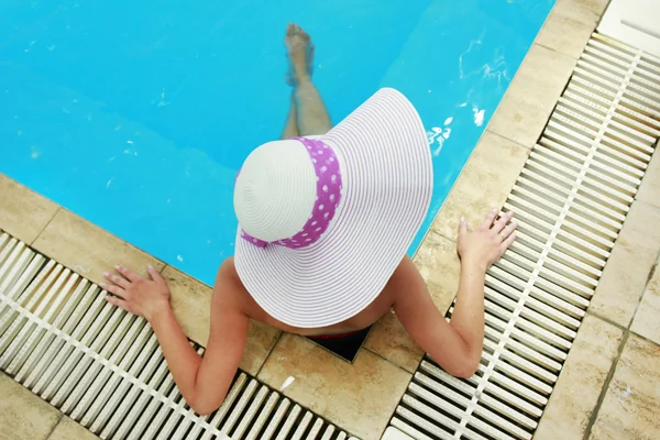 Menina em um chapéu na piscina de água — Fotografia de Stock