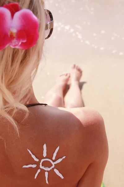 Di crema solare sulla schiena femminile sulla spiaggia — Foto Stock