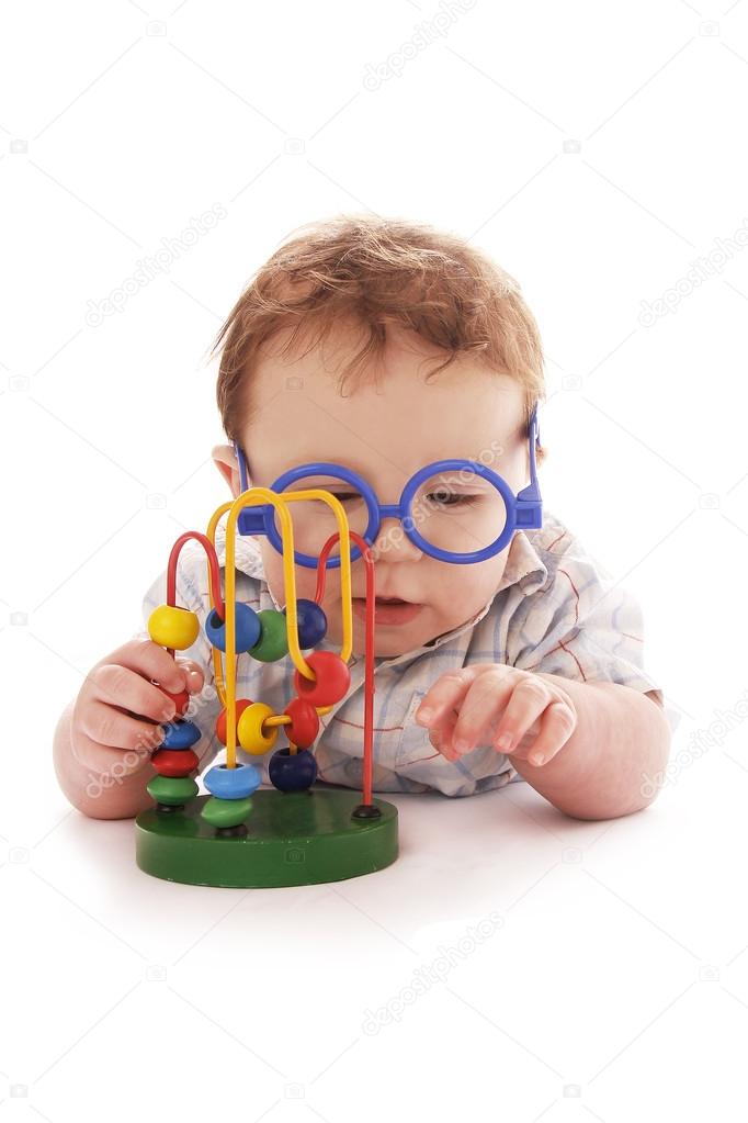 Infant baby on a white background in glasses with a toy
