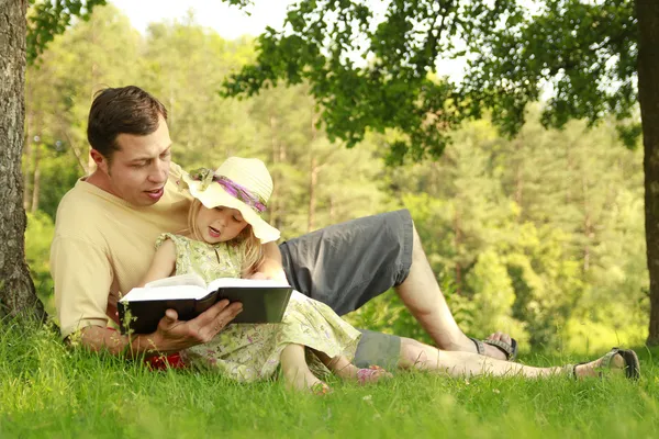 Padre joven con su pequeña hija lee la Biblia —  Fotos de Stock