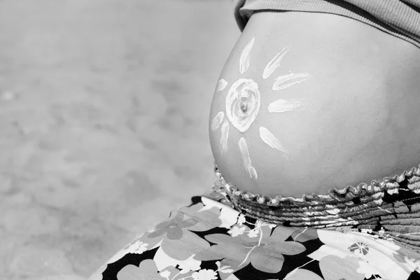 Of sun cream on a woman's pregnant belly on the beach — Stock fotografie