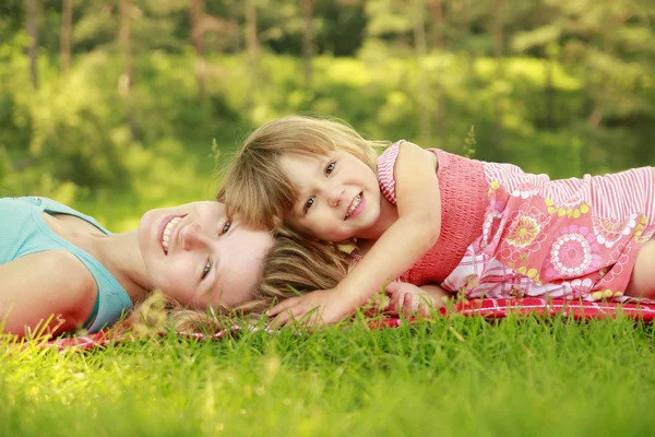 Jonge moeder en haar dochtertje spelen op gras — Stockfoto