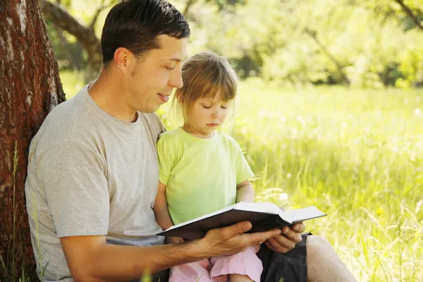 年轻的父亲带着女儿读圣经 》 — 图库照片