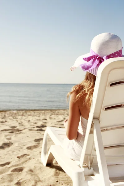 Menina de chapéu está deitada em uma cadeira de praia — Fotografia de Stock