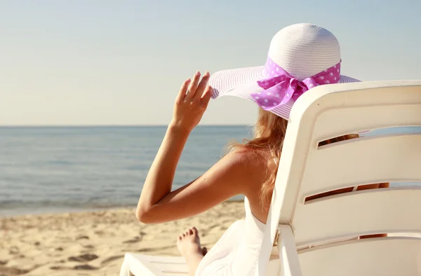 Menina de chapéu está deitada em uma cadeira de praia — Fotografia de Stock