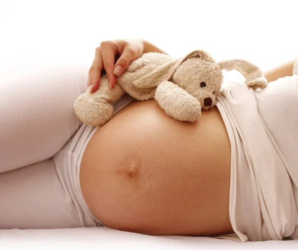 De zwangere vrouw maag met speelgoed — Stockfoto