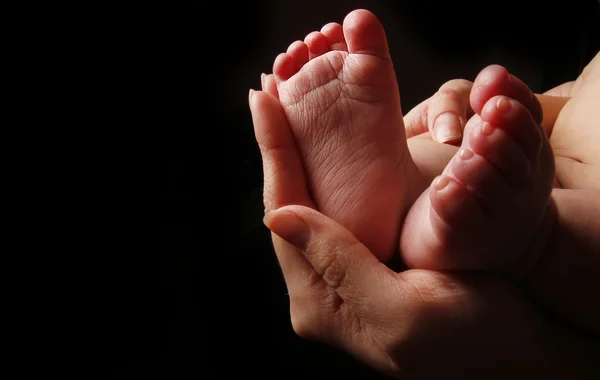 Novorozené nožky dítěte v rukou matky — Stock fotografie