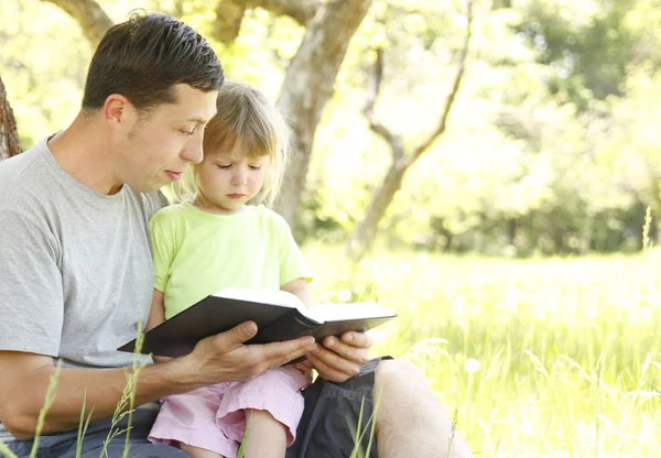 Padre con hija pequeña lee la Biblia — Foto de Stock