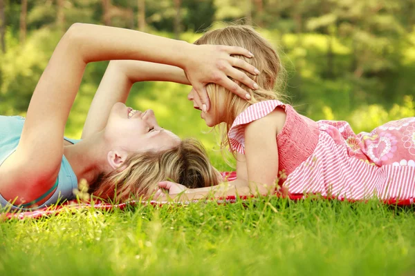 Mama and little daughter lie on the grass — Stock Photo, Image