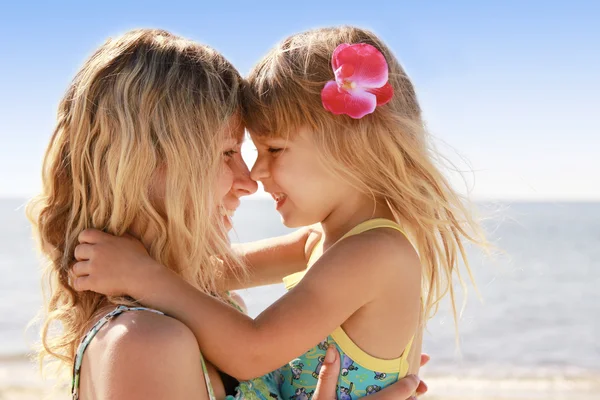 Mor med lilla dotter spelar på stranden — Stockfoto