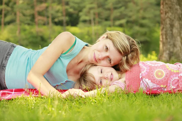 Mama en dochtertje liggen op het gras — Stockfoto