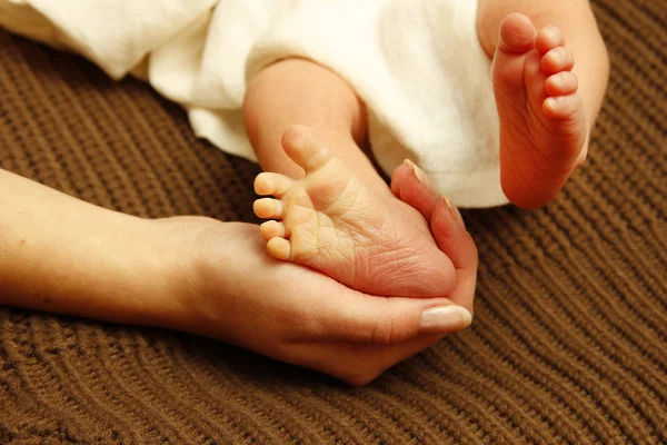 Benen weinig pasgeborene in van moeder handen — Stockfoto