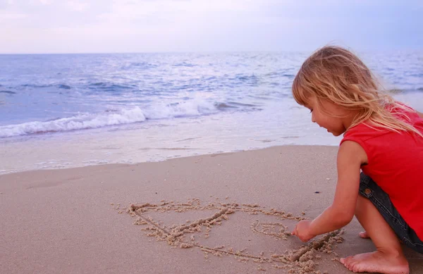 Little girl draws a house by the sea — Stock Photo, Image