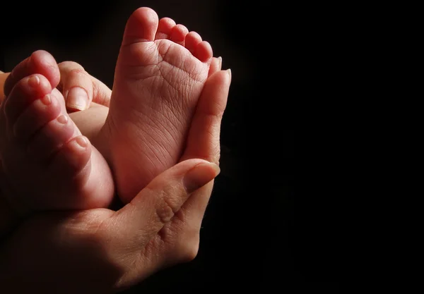 Nyfödda lilla baby fötter i mors händer — Stockfoto