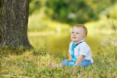 Küçük çocuk çimenlerde oturuyor.