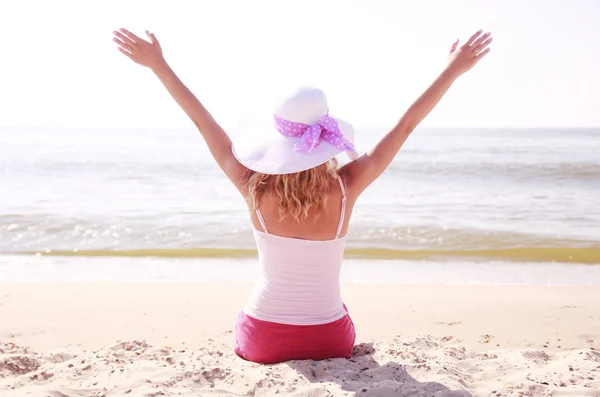 Chica en un sombrero sentado en la playa —  Fotos de Stock