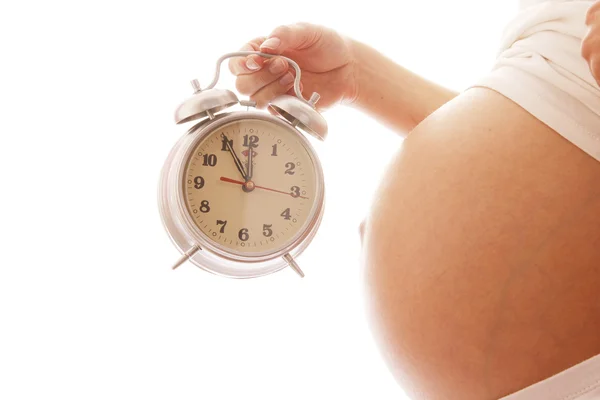 Беременная женщина с будильником — стоковое фото