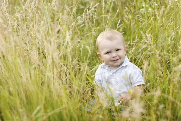 Liten pojke spelar i högt gräs — Stockfoto