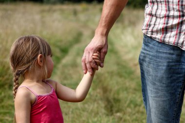 Ebeveyn, doğada küçük bir çocuğun elini tutar.