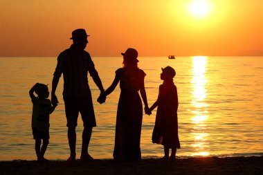 Aile silueti yazın gün batımında deniz kenarında