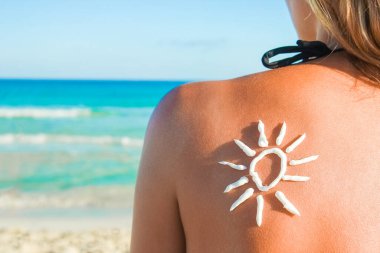 Sırtında güneş, doğada deniz kenarında mutlu bir kız.