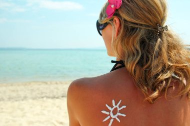 güneşten sahilde kadın sırtına krem