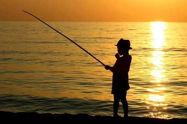 海に釣竿を持つ少年のシルエット — ストック写真