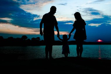 Deniz kenarında mutlu bir aile, doğanın siluetinde.